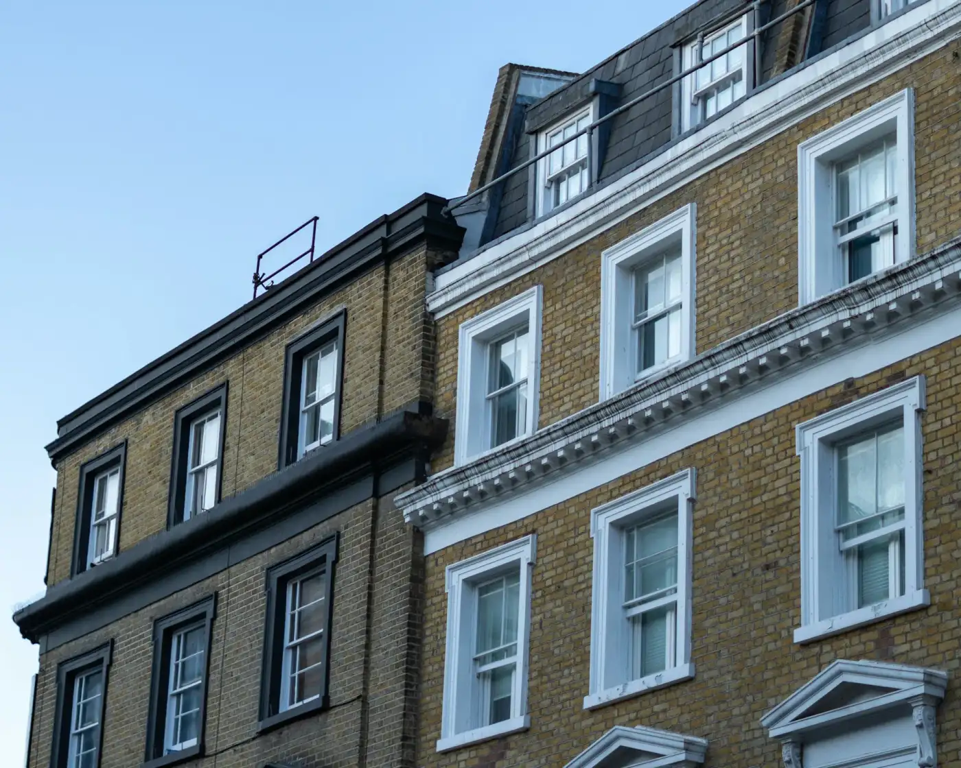 A street of yellow-brick terraced houses at dusk, East London